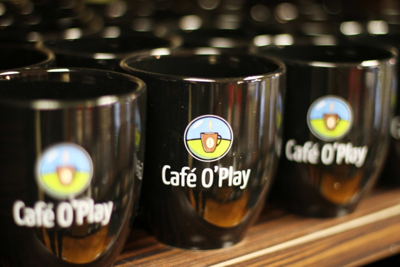 several coffee mugs with Cafe O Play logo